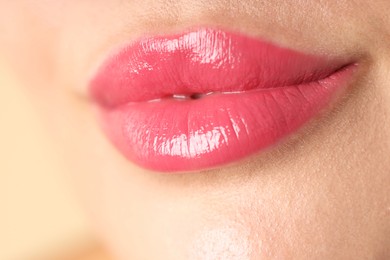 Photo of Woman with beautiful pink lipstick on her lips against beige background, macro view