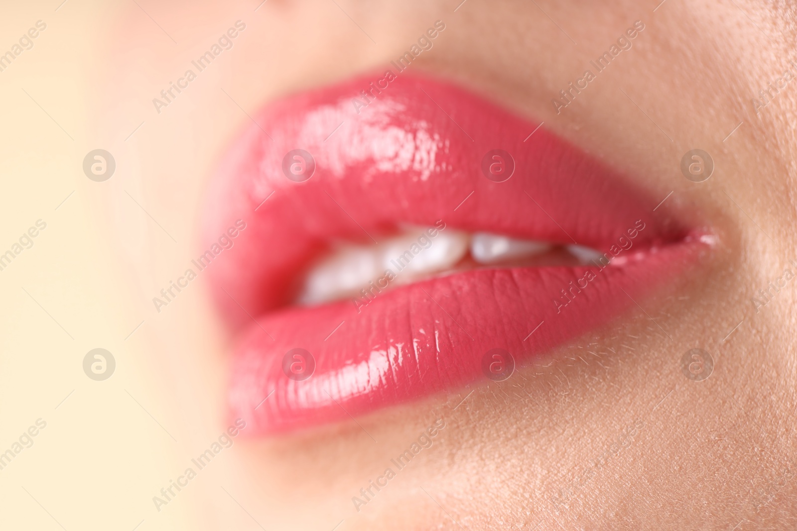 Photo of Woman with beautiful pink lipstick on her lips against beige background, macro view