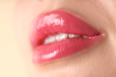 Photo of Woman with beautiful pink lipstick on her lips against beige background, macro view