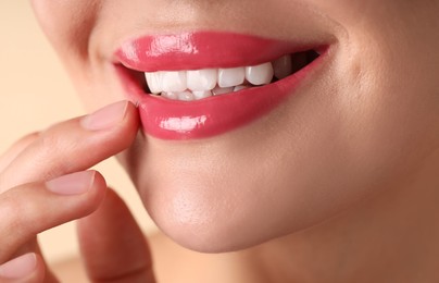 Photo of Woman with beautiful pink lipstick on her lips against beige background, macro view