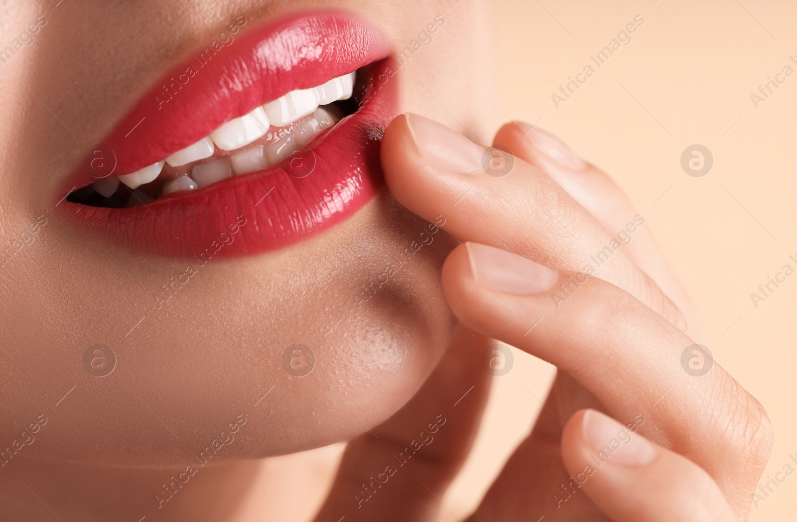 Photo of Woman with beautiful pink lipstick on her lips against beige background, macro view