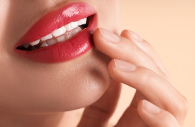 Photo of Woman with beautiful pink lipstick on her lips against beige background, macro view