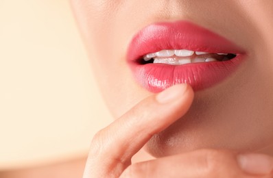 Photo of Woman with beautiful pink lipstick on her lips against beige background, macro view