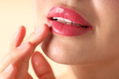 Photo of Woman with beautiful pink lipstick on her lips against beige background, macro view