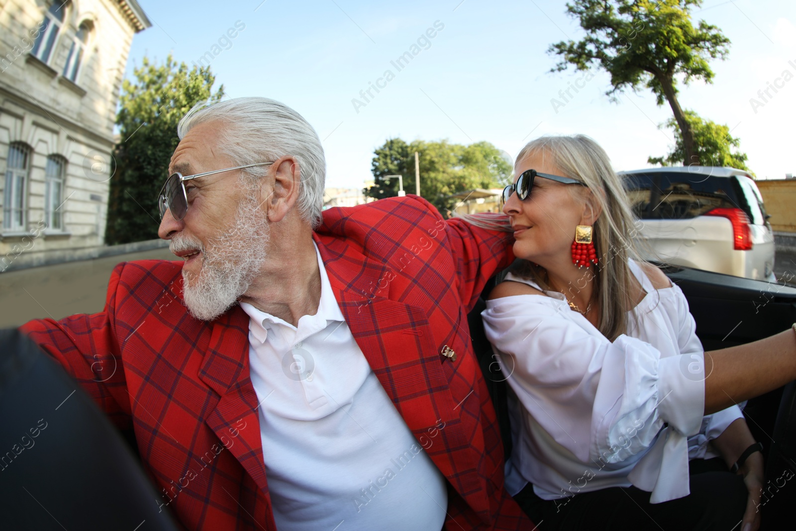 Photo of Senior couple enjoying cabriolet ride in city, wide angle lens