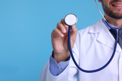 Photo of Pediatrician with stethoscope on light blue background, closeup. Space for text