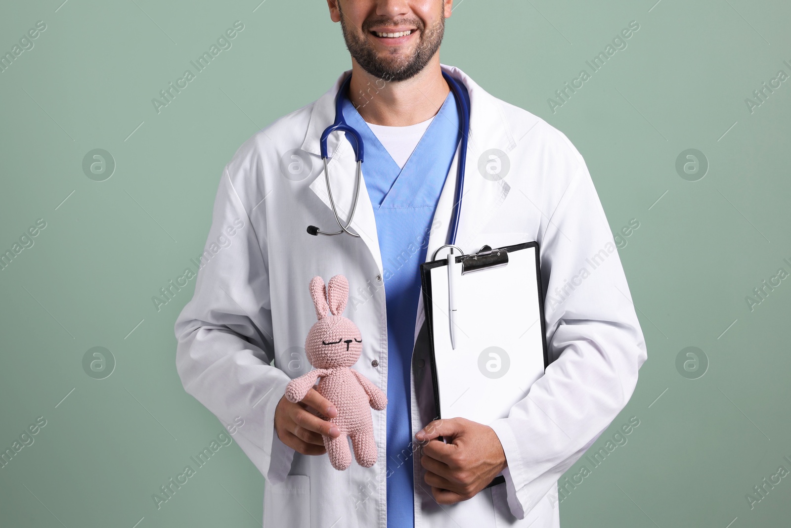 Photo of Pediatrician with clipboard and toy bunny on green background