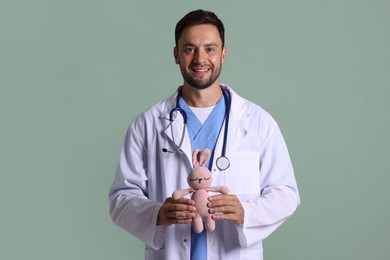 Photo of Pediatrician with toy bunny on green background