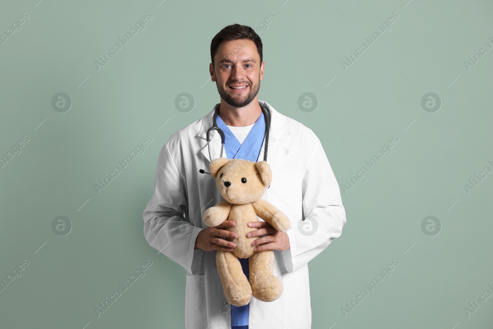 Photo of Pediatrician with teddy bear on green background