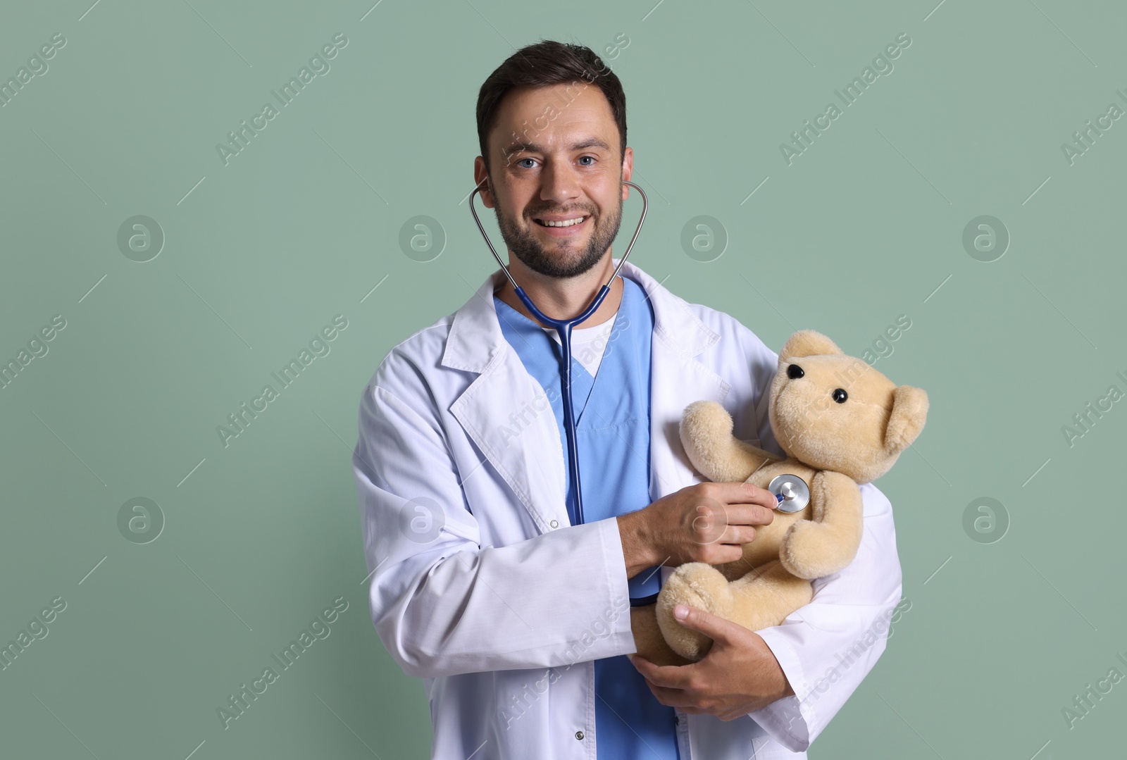 Photo of Pediatrician checking heartbeat of teddy bear on green background