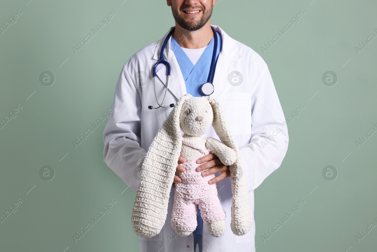 Photo of Pediatrician with toy bunny on green background, closeup