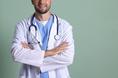 Photo of Pediatrician with stethoscope on green background, closeup. Space for text