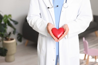 Photo of Pediatrician with heart model in hospital, closeup