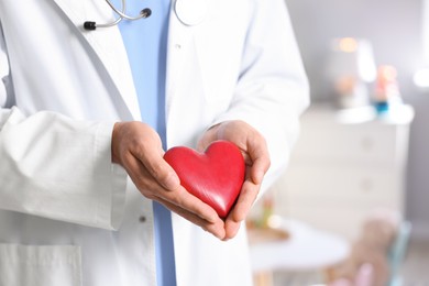 Photo of Pediatrician with heart model in hospital, closeup