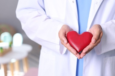 Photo of Pediatrician with heart model in hospital, closeup