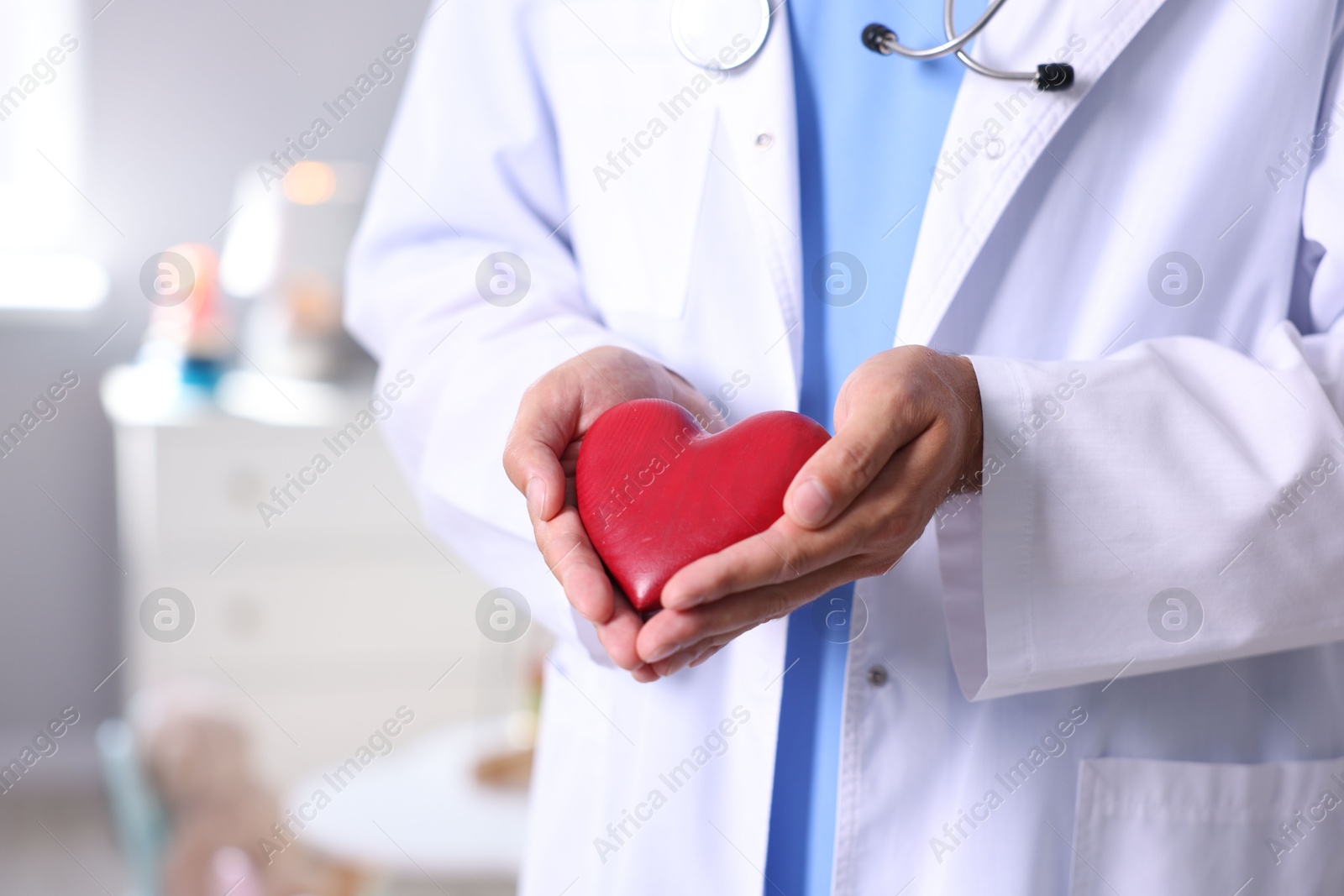 Photo of Pediatrician with heart model in hospital, closeup