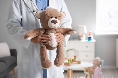 Photo of Pediatrician with teddy bear in hospital, closeup. Space for text
