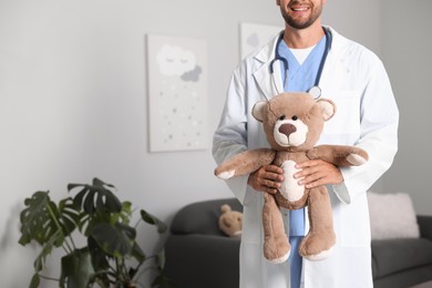 Photo of Pediatrician with teddy bear in hospital, closeup. Space for text