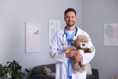 Photo of Professional pediatrician with teddy bear in hospital. Space for text