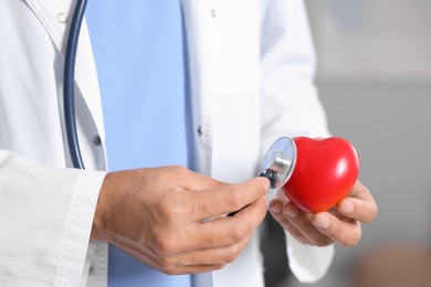 Photo of Pediatrician checking heartbeat of heart model in hospital, closeup