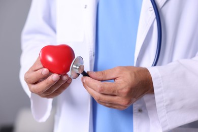 Photo of Pediatrician checking heartbeat of heart model in hospital, closeup