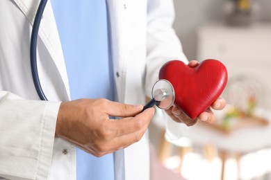 Photo of Pediatrician checking heartbeat of heart model in hospital, closeup