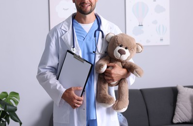 Photo of Pediatrician with teddy bear and clipboard in hospital, closeup