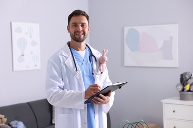 Photo of Pediatrician with clipboard writing notes in hospital. Space for text