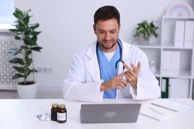 Photo of Pediatrician having video call with patient via laptop at desk in hospital