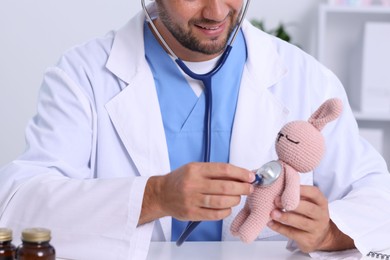 Photo of Pediatrician checking heartbeat of toy bunny in hospital, closeup