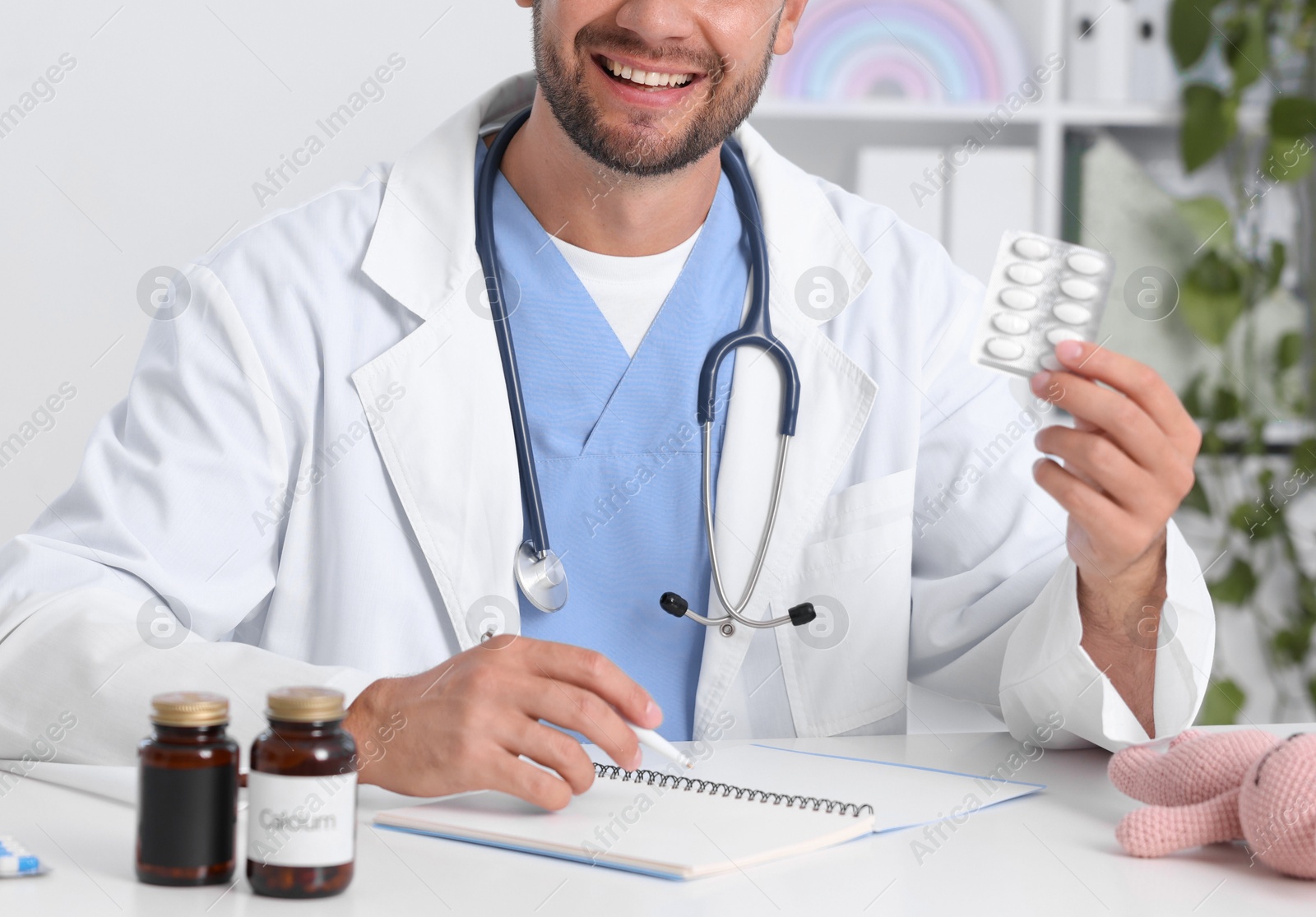 Photo of Pediatrician with pills and clipboard at desk in clinic, closeup