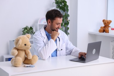 Photo of Pediatrician working with laptop at desk in hospital