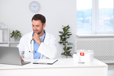Photo of Pediatrician working on laptop at desk in hospital
