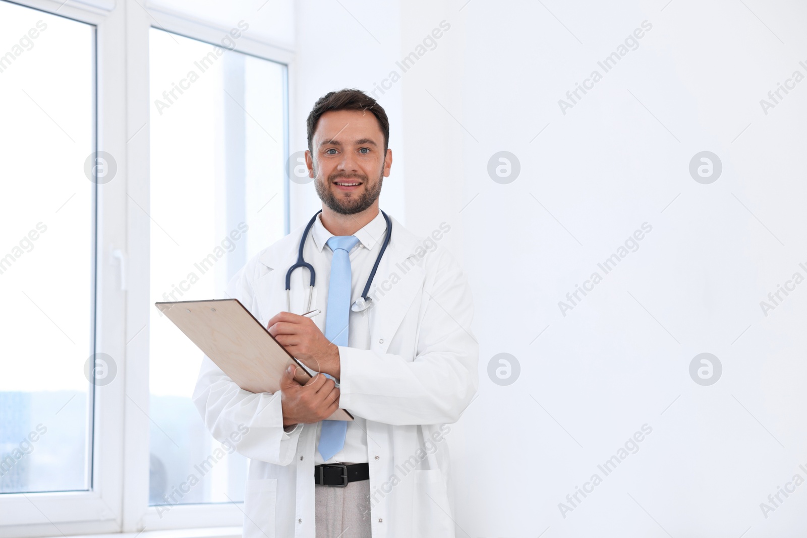 Pediatrician with stethoscope and clipboard in hospital. Space for text Photo of Pediatrician with stethoscope and clipboard in hospital. Space for text