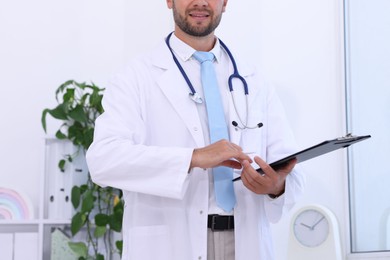 Photo of Pediatrician with stethoscope and clipboard in hospital, closeup