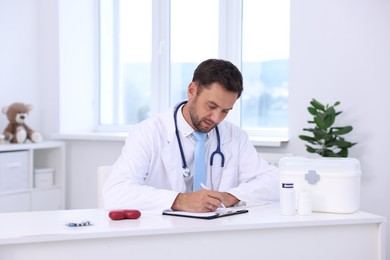 Photo of Professional pediatrician working at desk in hospital