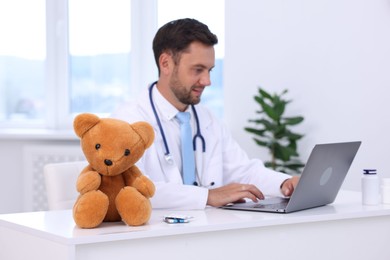 Photo of Pediatrician working on laptop at desk in hospital, selective focus