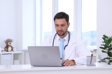 Photo of Pediatrician working on laptop at desk in hospital