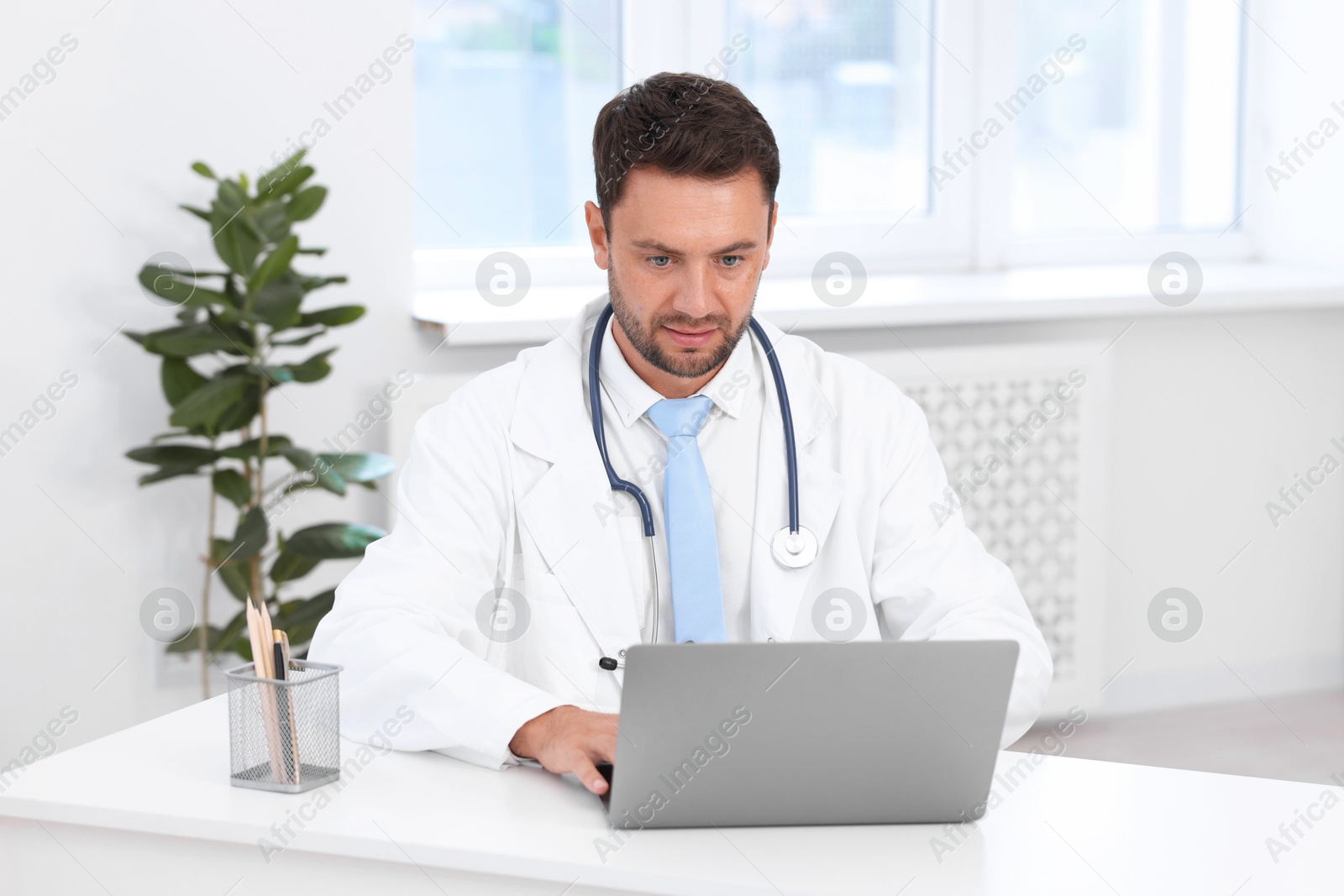 Pediatrician working on laptop at desk in hospital Photo of Pediatrician working on laptop at desk in hospital