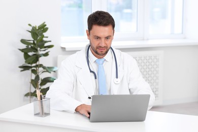 Photo of Pediatrician working on laptop at desk in hospital