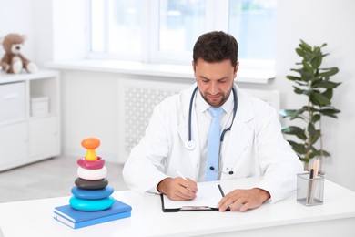 Photo of Professional pediatrician working at desk in hospital