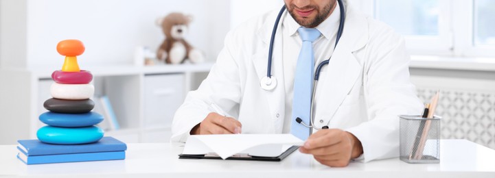 Photo of Pediatrician working at desk in hospital, closeup