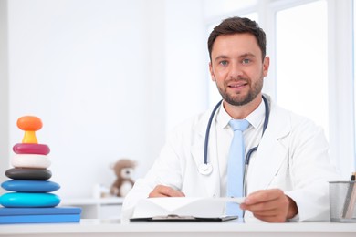 Photo of Professional pediatrician working at desk in hospital