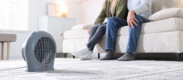 Photo of Couple on sofa near electric heater at home, selective focus