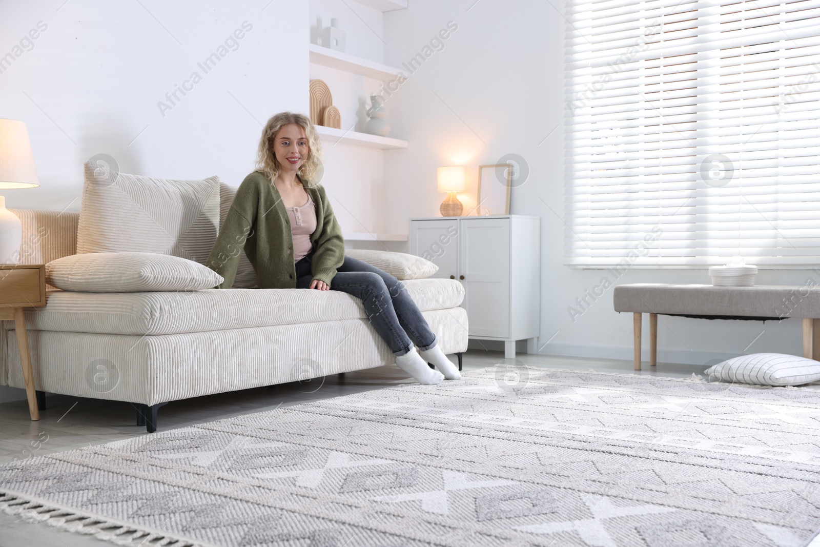 Photo of Happy young woman resting on sofa at home, space for text