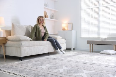 Photo of Happy young woman resting on sofa at home, space for text