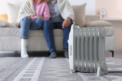 Photo of Couple on sofa near electric heater at home, selective focus
