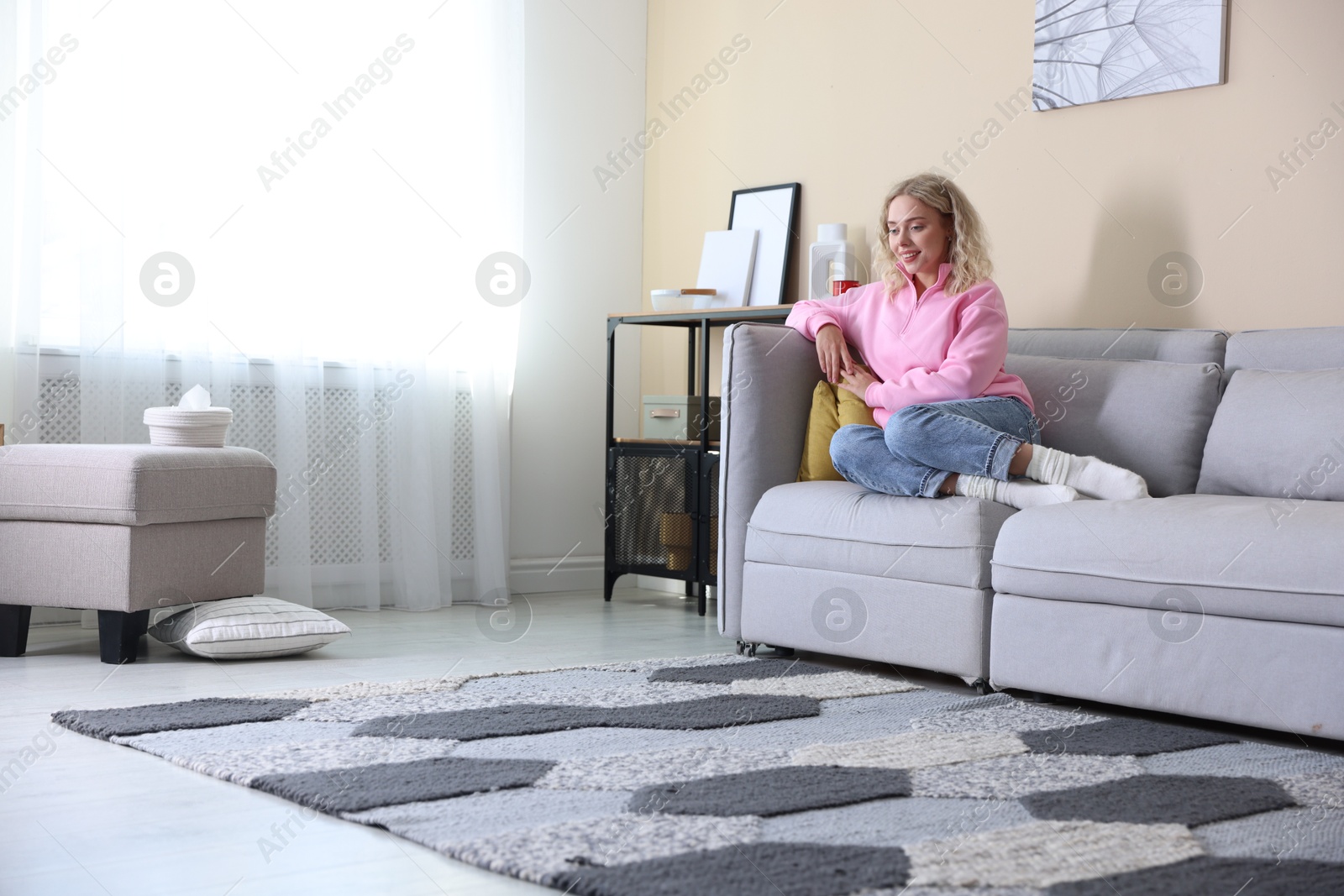 Photo of Happy young woman resting on sofa at home, space for text