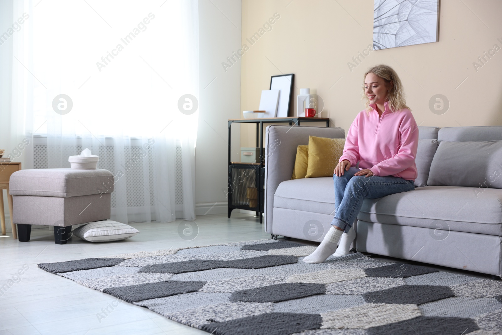 Photo of Happy young woman resting on sofa at home, space for text