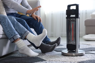 Photo of Couple near electric heater on floor at home, closeup